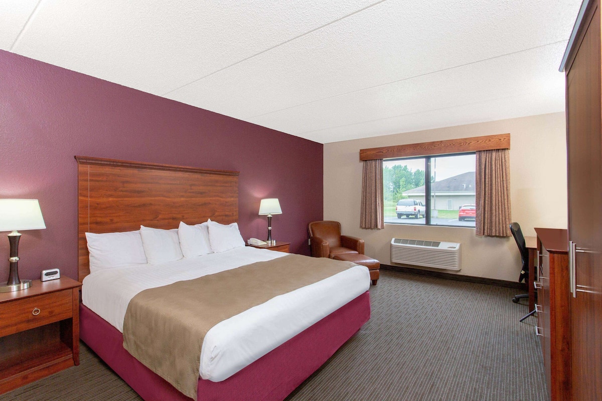 Hotelkamer met een groot bed, een bureau, een stoel, een raam met uitzicht op auto's en een airconditioning.