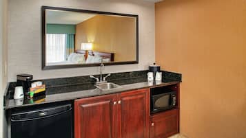 A hotel bathroom with a sink, mirror, and a microwave.
