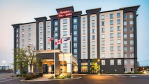 A Hampton Inn Suites hotel with a modern facade, multiple floors, and a well-lit entrance. - Hampton Inn & Suites by Hilton Toronto Airport (Mississauga)