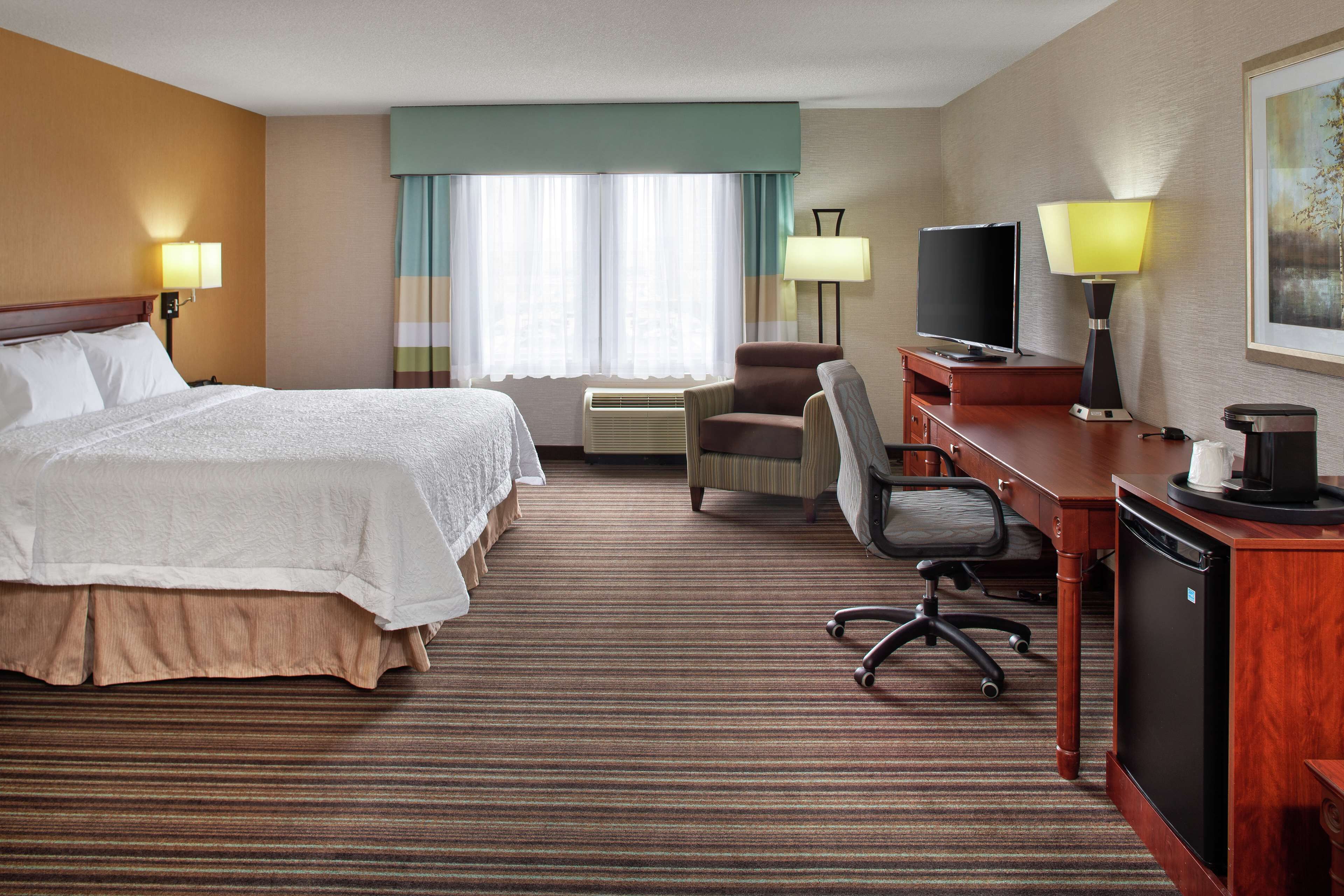 Une chambre d’hôtel avec un grand lit, un bureau avec un ordinateur, une chaise et un téléviseur.