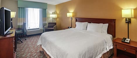 Habitación de hotel con una cama grande, dos mesitas de noche, un escritorio con computadora, una silla y un televisor.