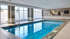 A large indoor swimming pool with clear water, tiled floor, and safety markings. - Hampton Inn & Suites by Hilton Toronto Airport (Mississauga)