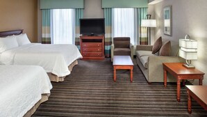 A hotel room with two beds, a television, a sofa, a chair, and a small table. - Hampton Inn & Suites by Hilton Toronto Airport (Mississauga)