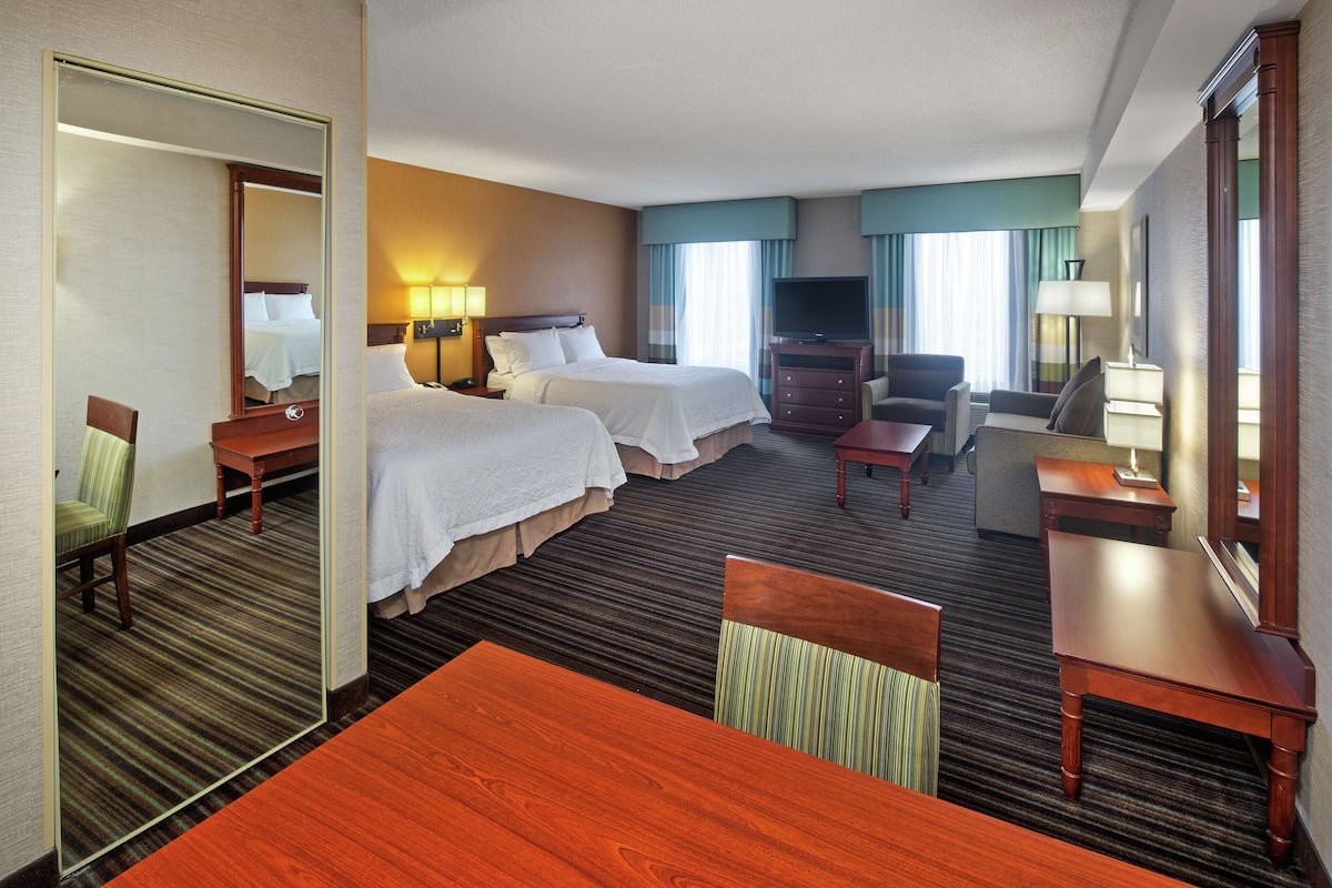 A hotel room with two beds, a TV, a desk, and a chair.