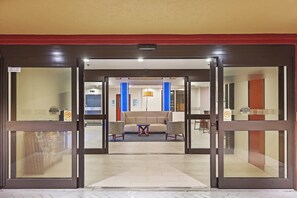 A hotel lobby with a reception desk, seating area, and a blue door. - Holiday Inn Express & Suites Houston - Memorial Park Area by IHG (Houston)
