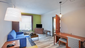 Une chambre d’hôtel moderne équipée d’un canapé, d’une table à manger avec des chaises, d’une télévision et d’une lampe.