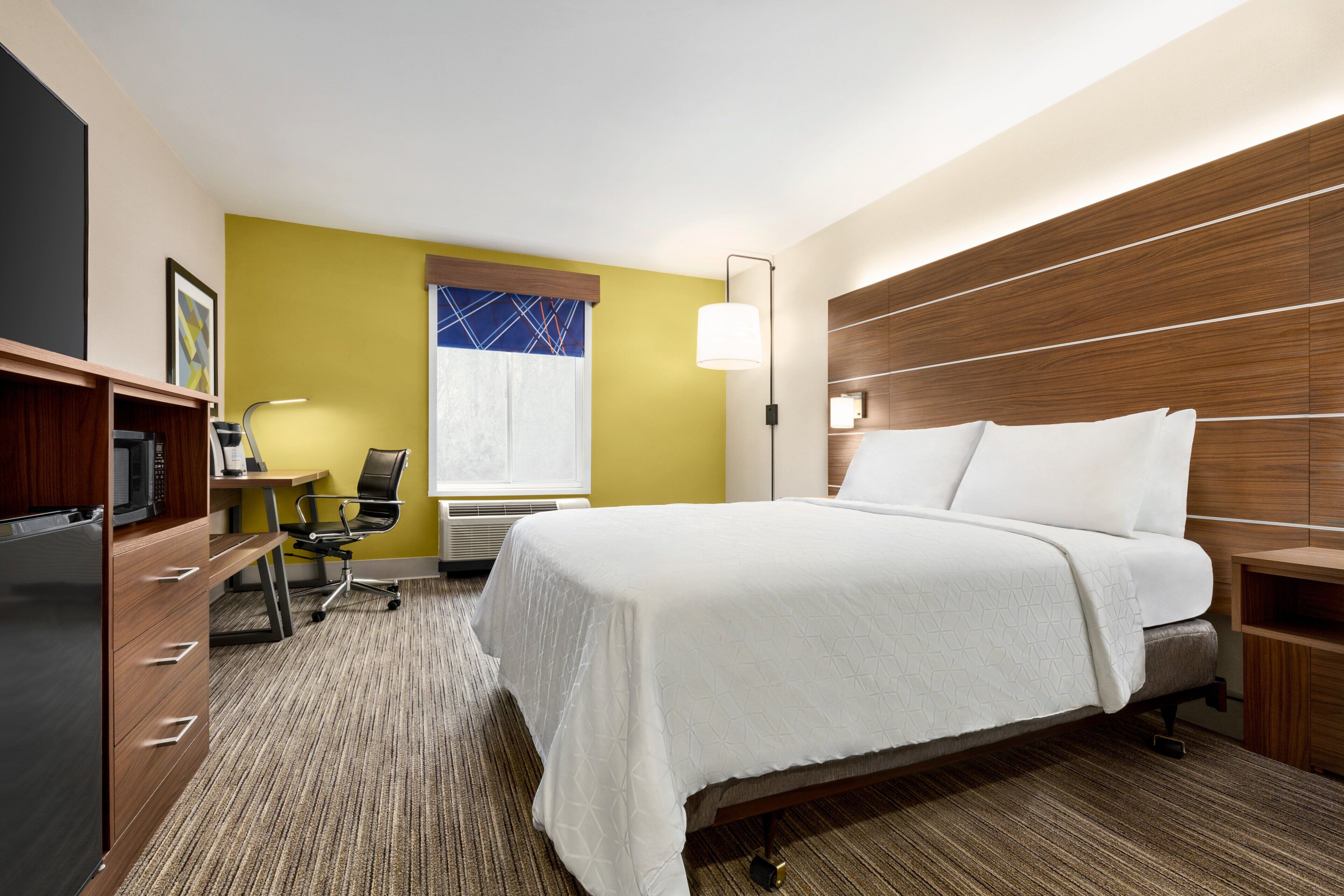 Une chambre d’hôtel équipée d’un lit, d’un bureau, d’une chaise et d’un téléviseur.