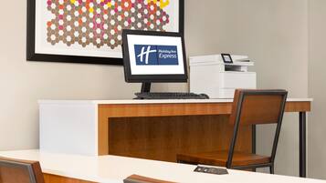 A reception desk with a monitor displaying the Holiday Inn Express logo, a printer, and a keyboard.