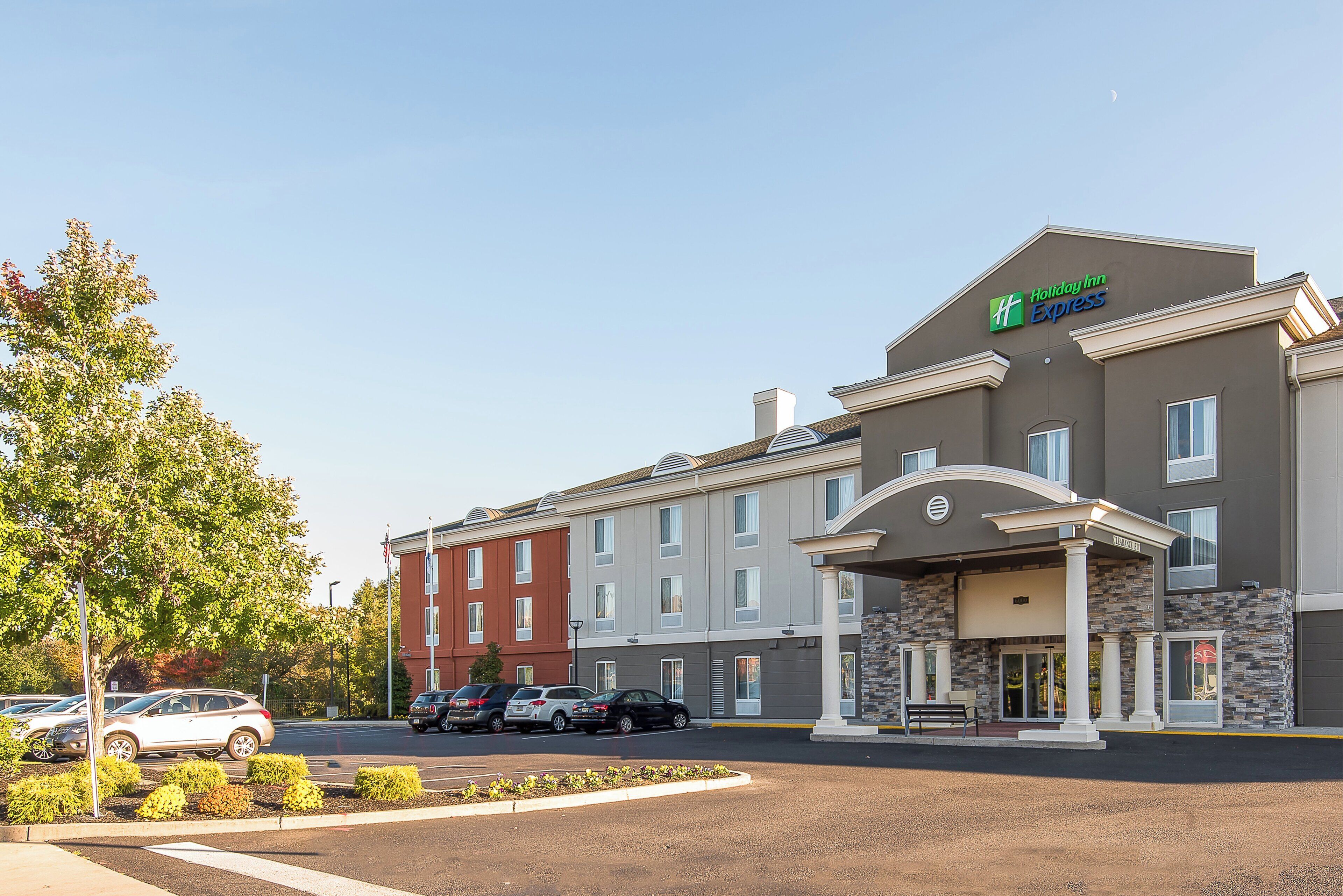 Edificio de Holiday Inn Express con estacionamiento y varios autos.