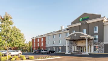 Edificio de Holiday Inn Express con estacionamiento y varios autos.