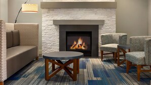 A modern living room with a fireplace, a sofa, two armchairs, a coffee table, and a floor lamp. - Holiday Inn Express & Suites Philadelphia - Mt. Laurel by IHG (Mount Laurel)