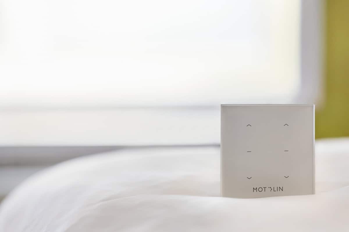 A white bedside table with a small rectangular object on it, possibly a remote control or a book.