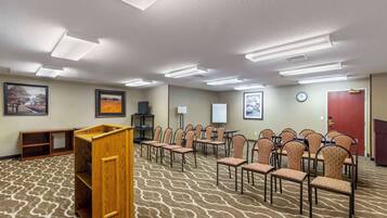 A conference room with a patterned carpet, wooden podium, and rows of chairs.