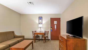 Una habitación de hotel con sofá, una mesa de madera, televisor y cómoda.