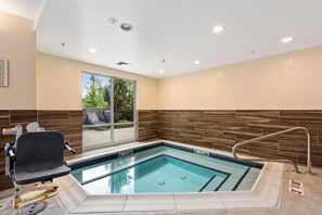 A small indoor pool with a wheelchair-accessible bench, a window with a view of trees, and a tiled wall. - Fairfield Inn & Suites by Marriott Bend Downtown (Bend)