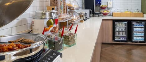 A buffet setup with various food items and a self-service hot plate.