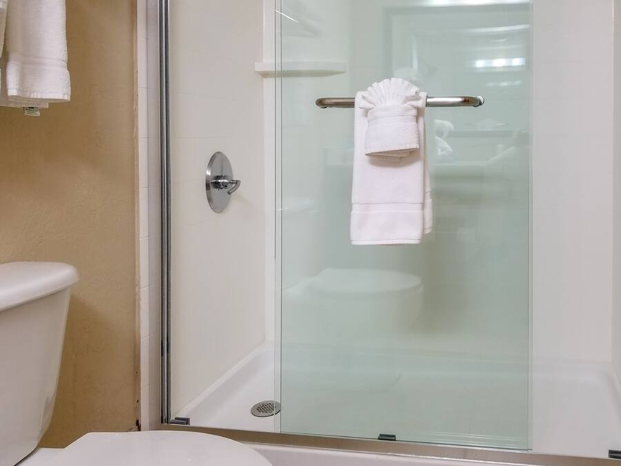 Un baño con cabina de ducha de vidrio, inodoro y perchero con toallas.