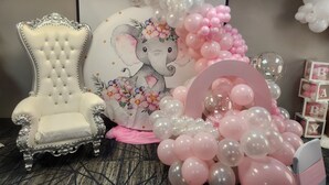 A room with a tufted armchair, a floral elephant-themed backdrop, and a balloon arrangement. - Holiday Inn Express & Suites Orange City - Deltona by IHG (Orange City)