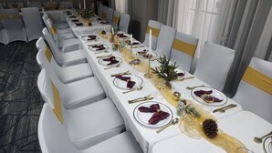 A long banquet table set with white tablecloths, gold accents, and red napkins. - Holiday Inn Express & Suites Orange City - Deltona by IHG (Orange City)