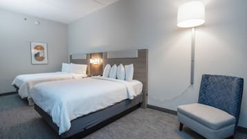 Une chambre d’hôtel avec deux lits, une chaise et une lampe fixée au mur.