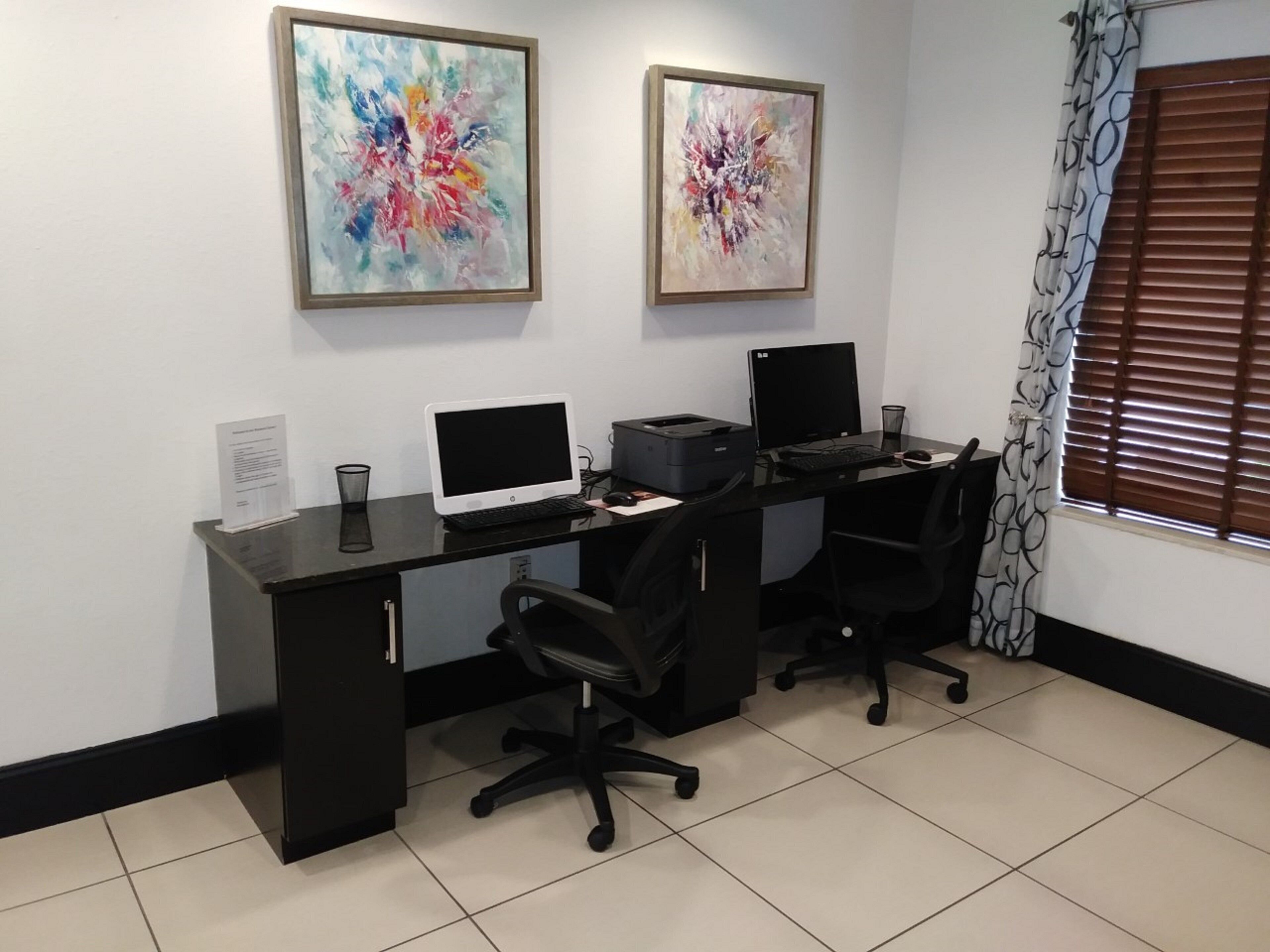 Ein professionelles Büro mit zwei Schreibtischen, Stühlen, Computern und einem Drucker.