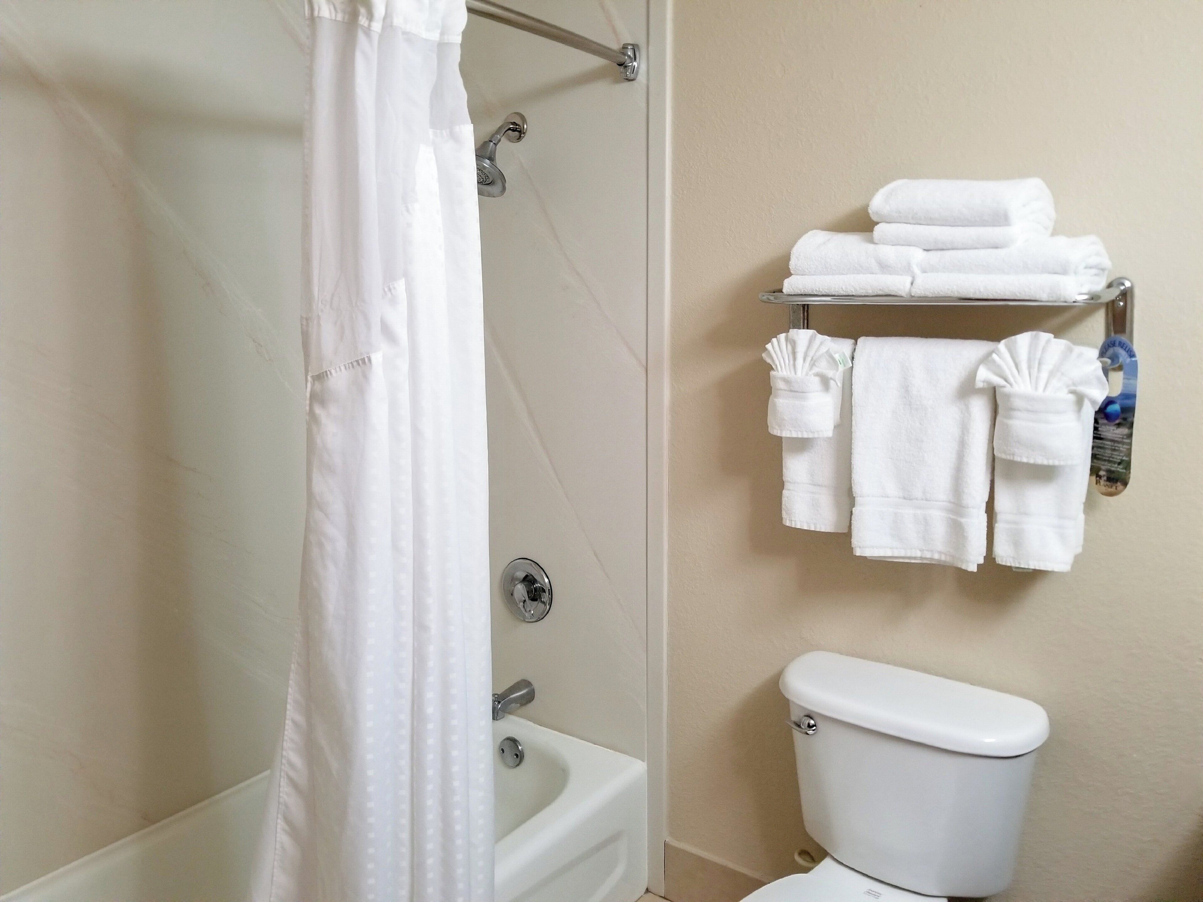 A bathroom with a bathtub, toilet, and a towel rack with folded towels.