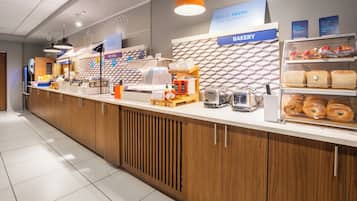 Eine Theke einer Bäckerei mit verschiedenen Brotsorten und Gebäck, einer Kaffeemaschine und Gewürzspendern.