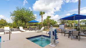 An outdoor pool area with lounge chairs, umbrellas, and a poolside table. - Holiday Inn Express & Suites Orange City - Deltona by IHG (Orange City)