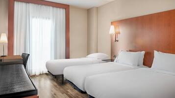 A hotel room with two single beds, a desk, and a chair.