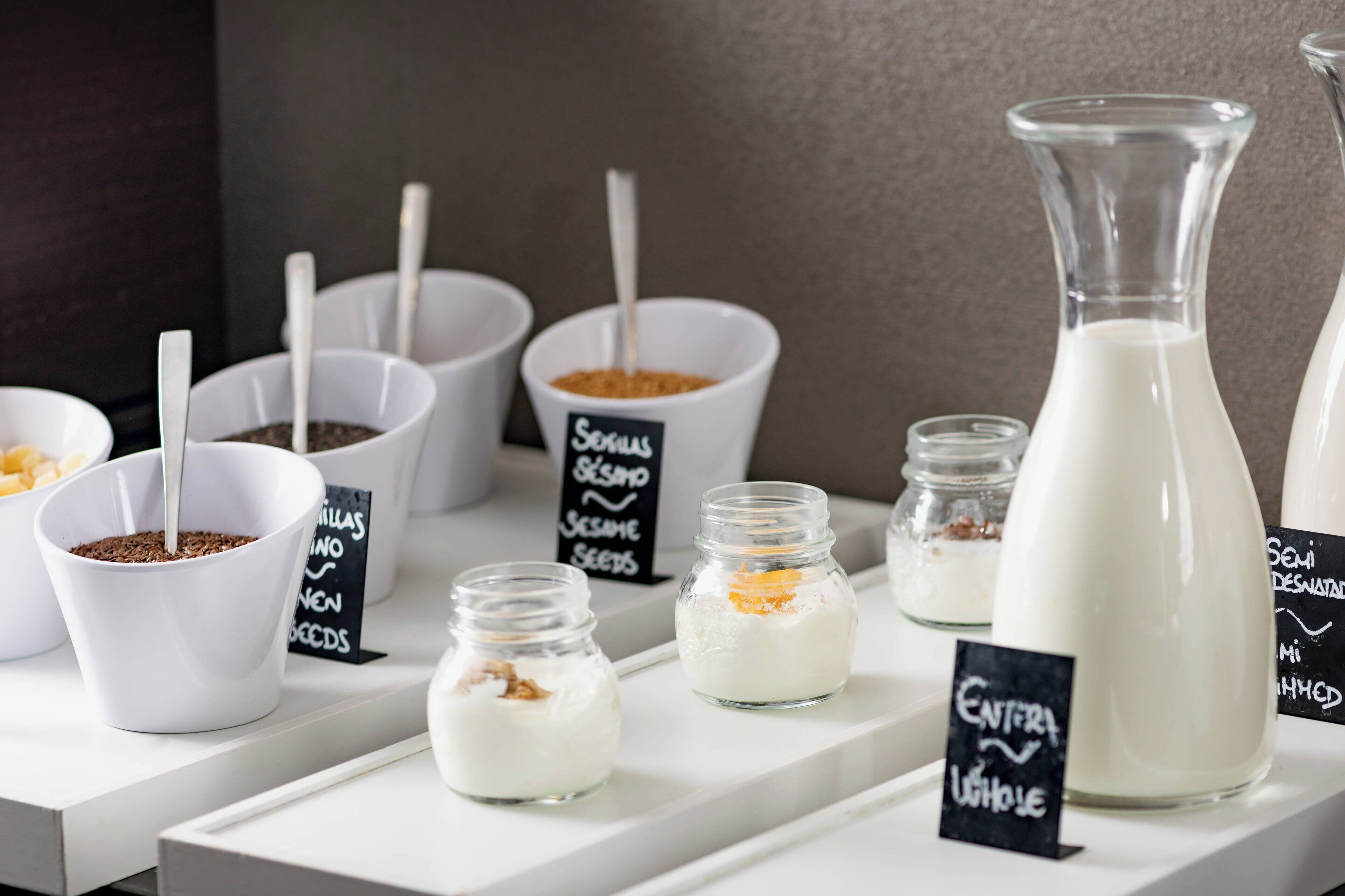 A display of various food items including bowls of seeds and a large bottle of milk.