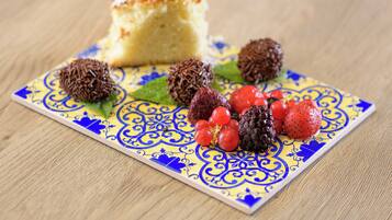 Un plato de postre con una rebanada de pastel, trufas de chocolate y frutos rojos sobre baldosas estampadas.
