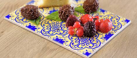 A dessert plate with a slice of cake, chocolate truffles, and berries on a patterned tile.