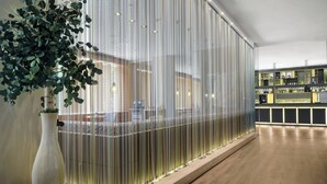 Un intérieur moderne avec un plancher en bois, une plante décorative et un mur orné d’un motif.
