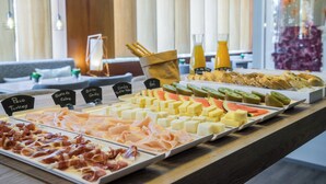 Un buffet proposant une variété de plats, notamment des viandes, des fromages et des fruits.
