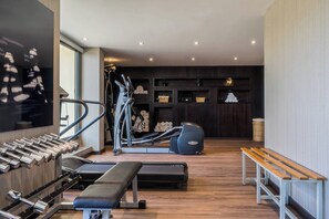 Un gimnasio moderno con equipo de ejercicio, una banca y un estante de pared.