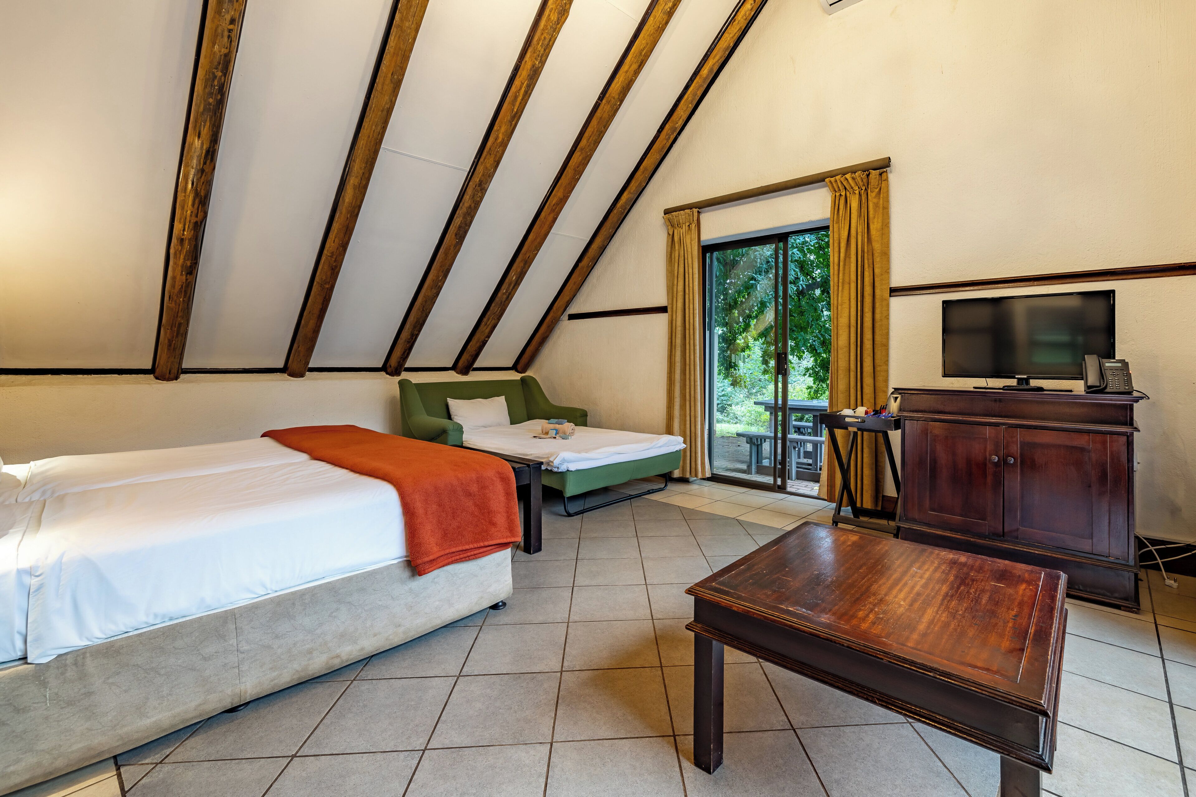 Une pièce comprenant un lit, un canapé, une télévision et une armoire en bois.