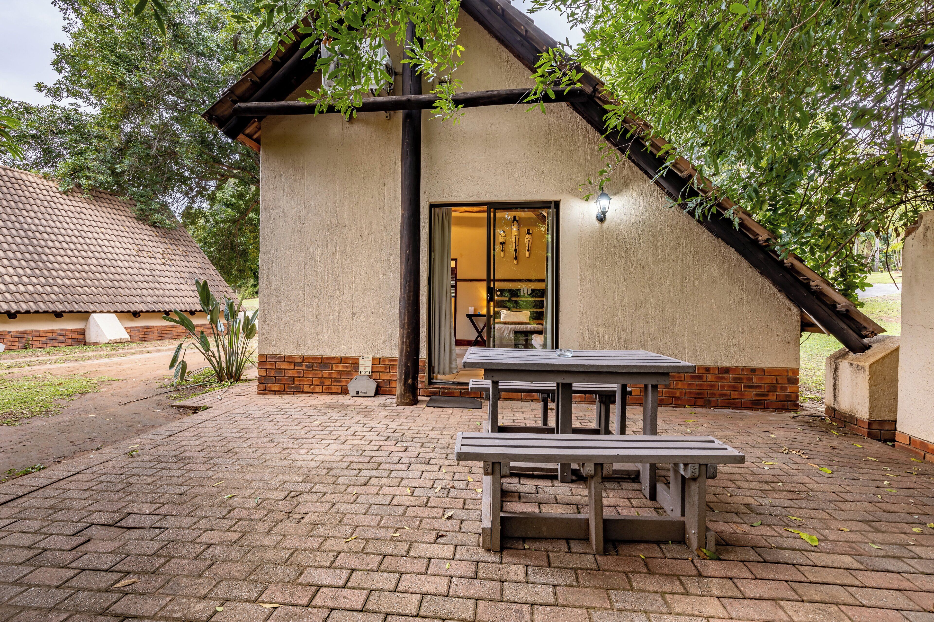 A building with a brick exterior, a tiled roof, and a picnic table in the foreground.