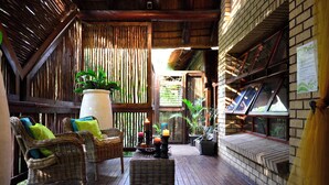A wooden deck with wicker furniture, candles, and potted plants. - Pestana Kruger Lodge (Nkomazi)
