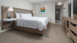 Una habitación de hotel con una cama grande, mesitas de noche, un escritorio y un cuadro en la pared.