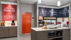 Un área de cocina moderna con una estación de gofres, una cafetera y un microondas.