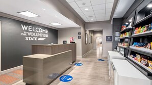 Un área de recepción moderna con un letrero que dice 'Welcome to the Volunteer State', un mostrador de recepción y una barra de aperitivos con diferentes opciones de comida.