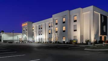 A modern hotel with a flat facade, multiple windows, and a parking lot.