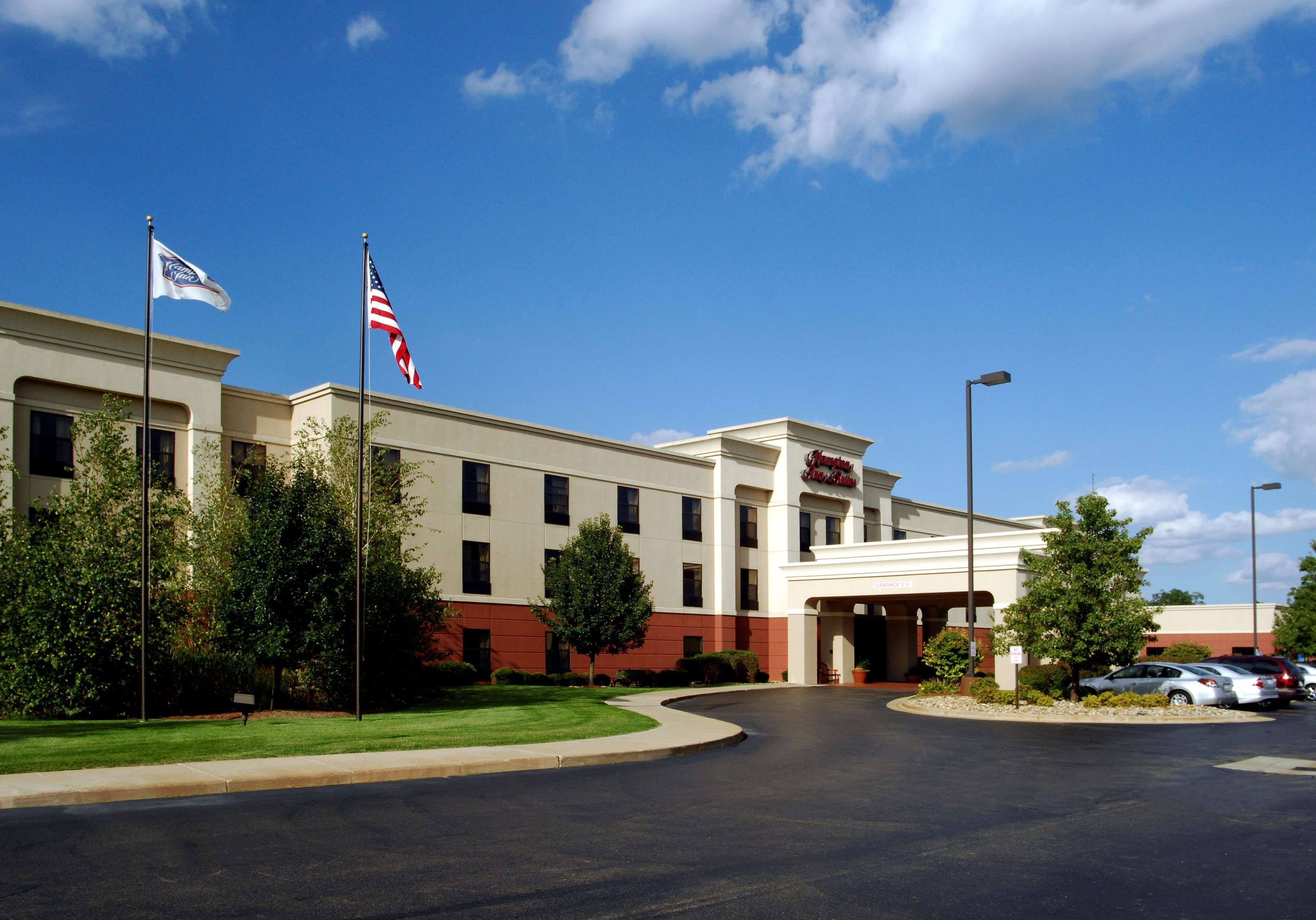 A hotel with a large parking lot, a flagpole with an American flag, and a sign indicating it is a Marriott hotel.