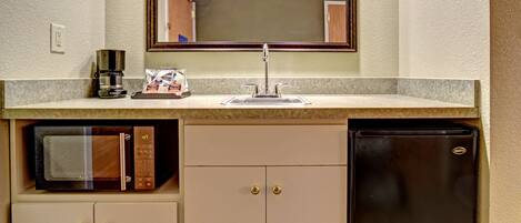 A compact kitchenette with a microwave, coffee maker, and refrigerator.