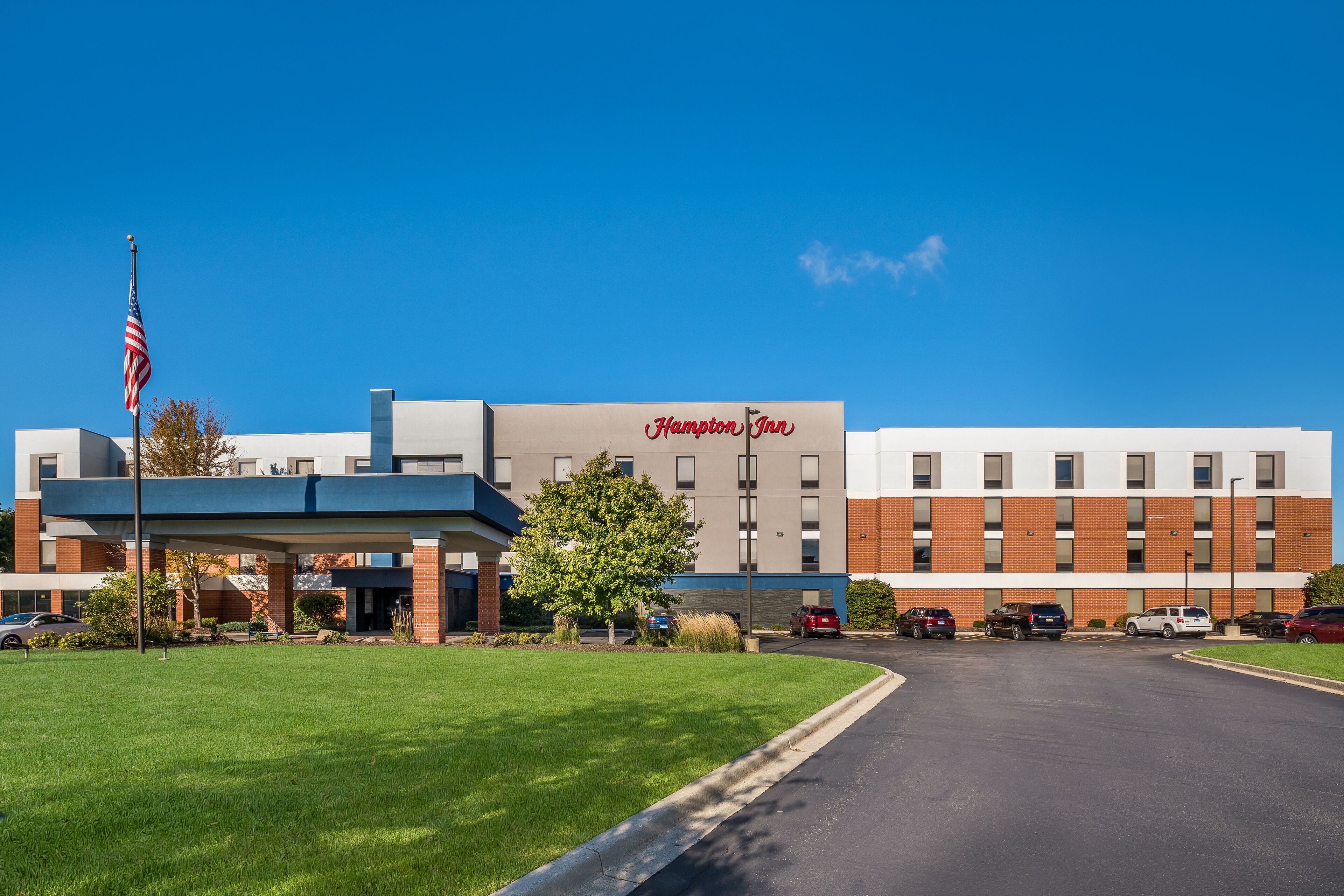 A Hampton Inn hotel with a parking lot and a clear blue sky.