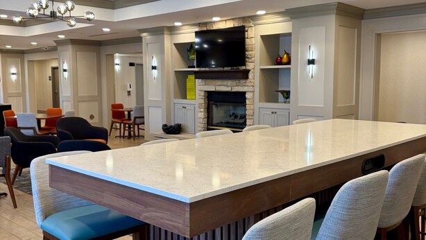 A spacious living area with a large island, bar stools, a flat-screen TV, and a fireplace.