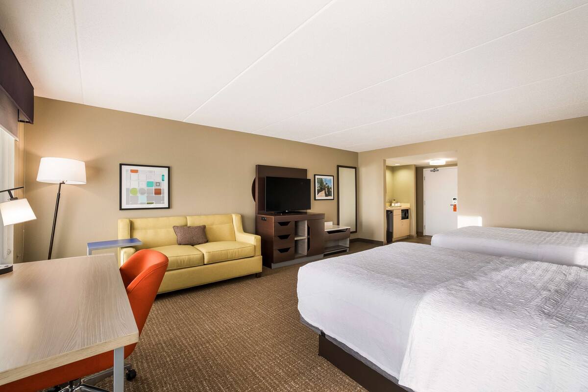 Hotelkamer met een bed, bureau, stoel, bank, televisie en dressoir.