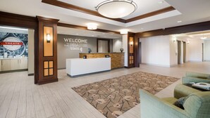 A hotel lobby with a reception desk, a large floral rug, and seating area.