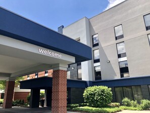 A modern building with a 'welcome' sign, large windows, and a covered entrance area.