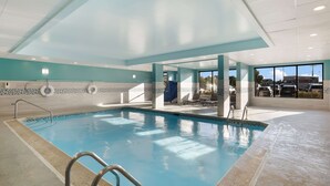 An indoor swimming pool with clear blue water, tiled walls, and a ceiling with skylights.